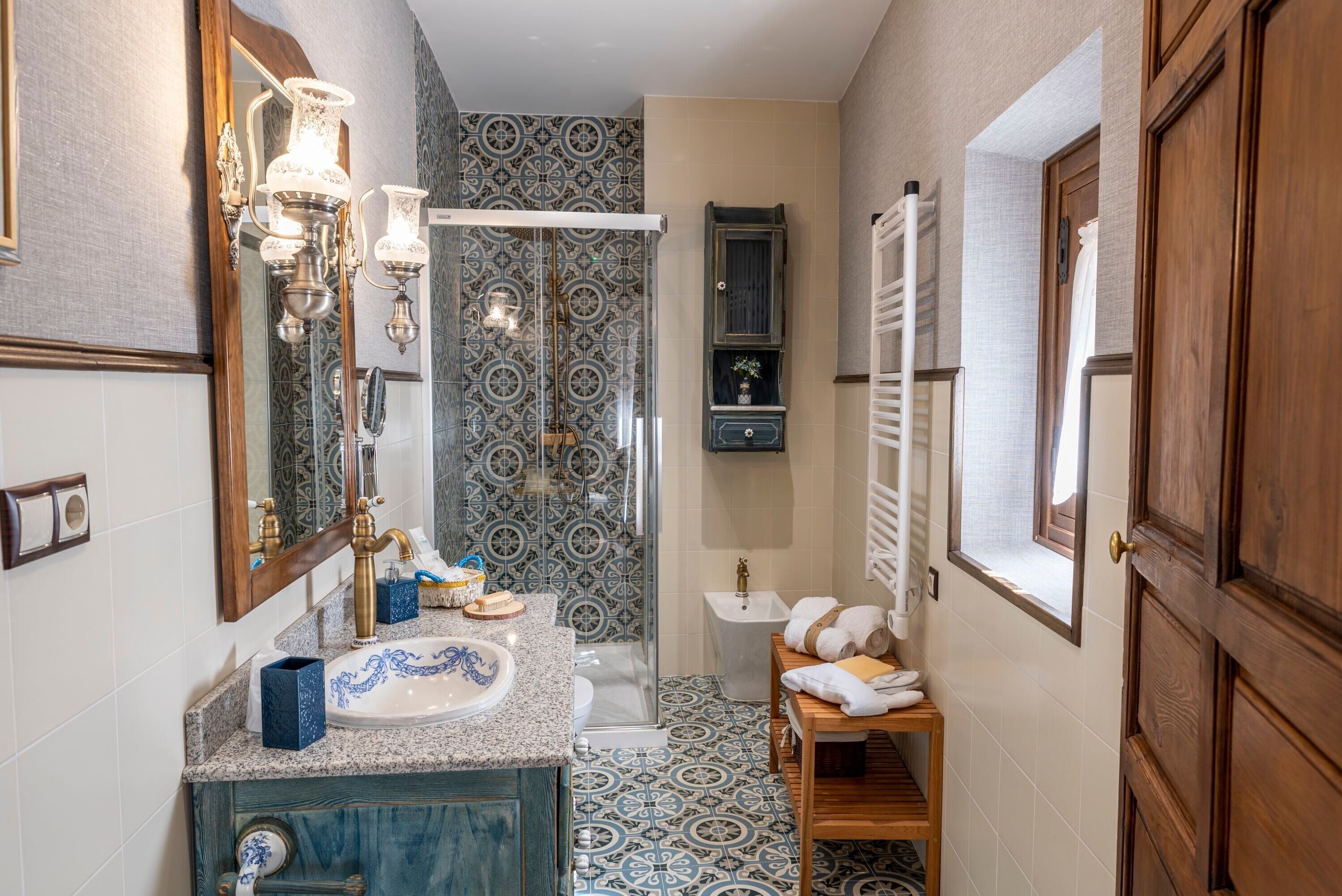 Baño con lavamanos, espejo, ducha y tocador de madera.