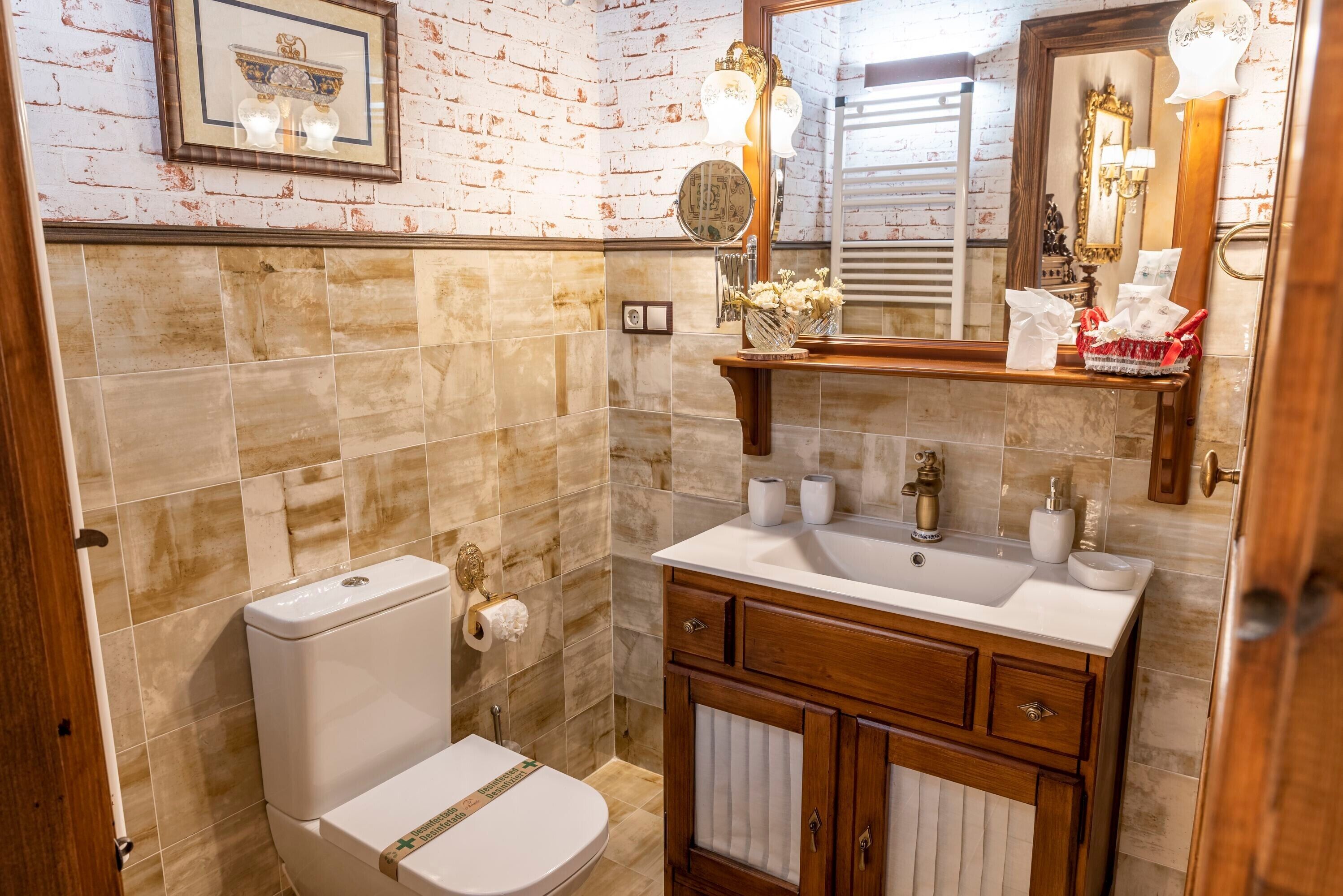 Un baño con inodoro, lavamanos, tocador y espejo.