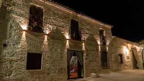 Un bâtiment en pierre doté de nombreuses fenêtres et de balcons, éclairé par un système d’éclairage extérieur.