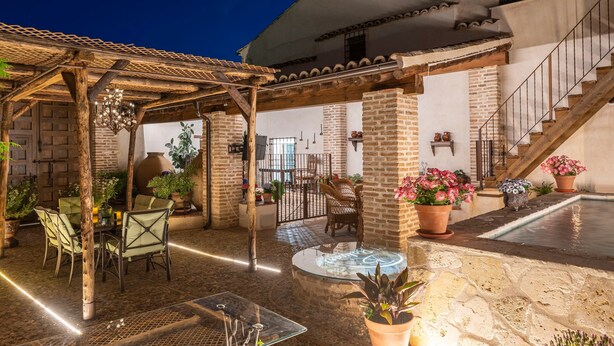 Une terrasse extérieure couverte, équipée d’une table et de chaises, d’un jacuzzi et de plantes en pot.