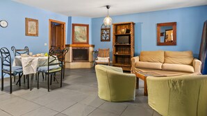 Ein Wohnzimmer mit Sofa, Sesseln, einem Esstisch und einem Kamin.