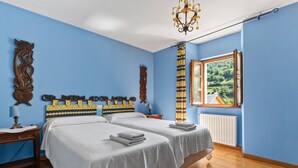 Ein Schlafzimmer mit zwei Betten, einem Fenster mit Aussicht und einer Chandelüster.