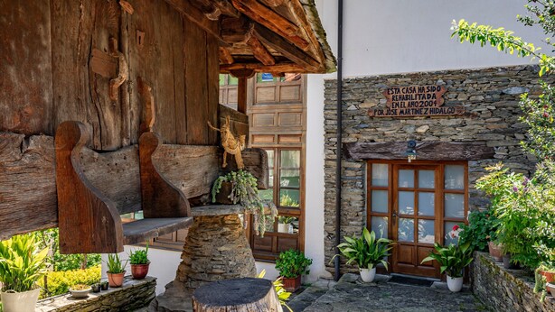 Ein rustikales Steinhaus mit Holzbalken, einer Holztreppe und Kübelpflanzen.