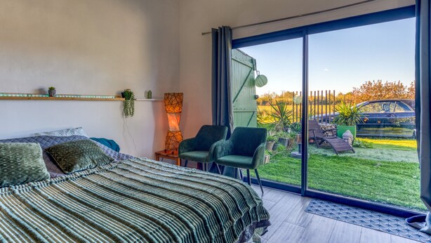 Un dormitorio con una cama grande, una silla, una lámpara y vistas al exterior.