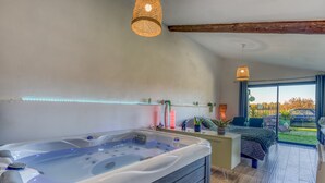 Un moderno spa con jacuzzi, un escritorio, una cama y un amplio ventanal con vistas al exterior.