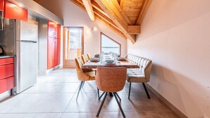 Una cocina moderna con un refrigerador de acero inoxidable, armarios rojos y techo de madera.