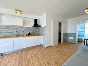 Uma cozinha moderna com bancada de madeira, armários brancos e painel de azulejos cinza.