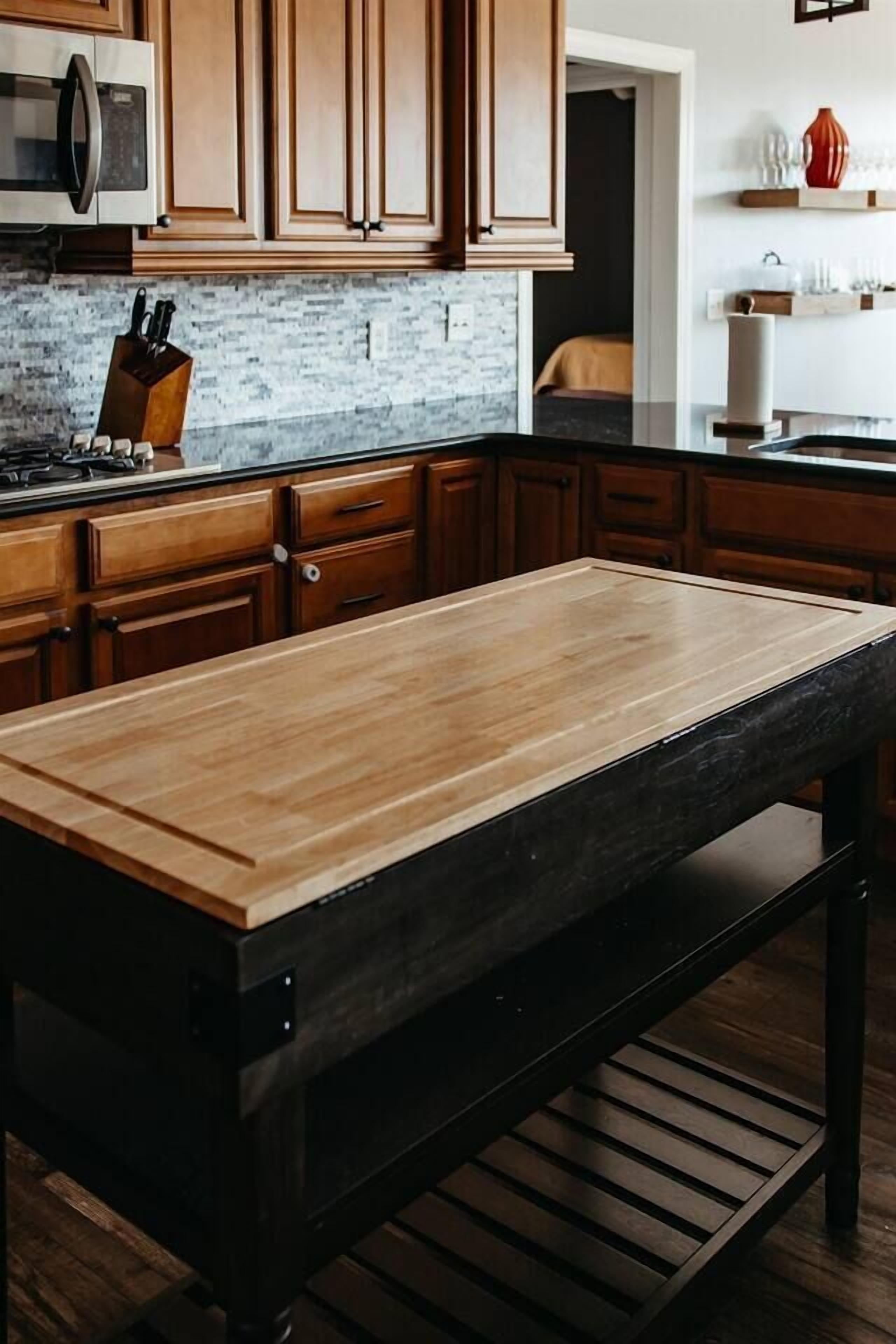 Una cucina con mobili in legno, un piano di lavoro in granito e un tavolo in metallo nero.
