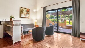 A living room with a sofa, two armchairs, a coffee table, a TV, a painting, and a view of an outdoor patio with a pergola. - Villa '25 Lola Flores' with Private Terrace, Wi-Fi and Air Conditioning (Ramatuelle)