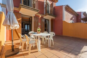 Un patio con mesa y sillas, un escoba y una planta en maceta.