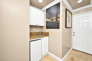 Compact kitchen with white cabinetry, granite countertop, and stainless steel sink.
