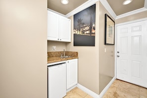 Compact kitchen with white cabinetry, granite countertop, and stainless steel sink.