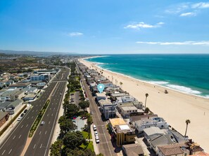 An aerial view of a coastal city with a wide road, beachfront, and buildings. - Duplex home only 1 home from the Sand in W. NPB (Newport Beach)