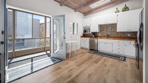 A modern kitchen with white cabinets, a wooden countertop, and a large window.