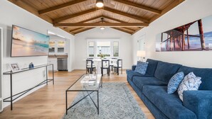 A spacious living area with a high ceiling, a dining area, and a kitchen.