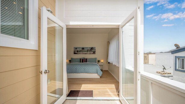 Una camera da letto con un letto, un comodino, un quadro e vista mare da una porta aperta.
