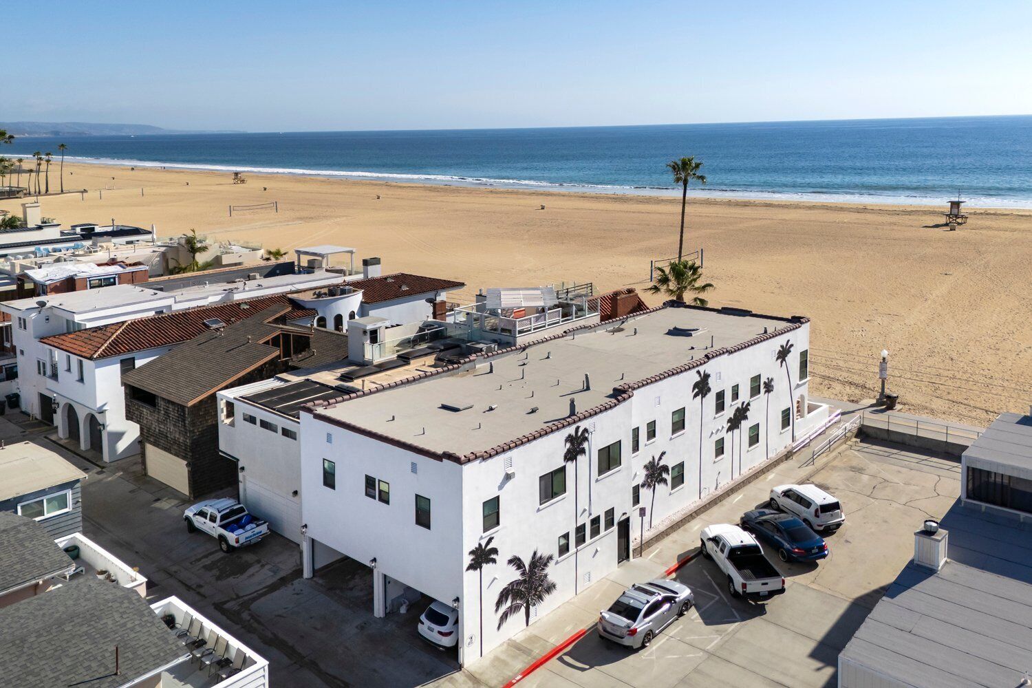 Ein Strandhotel mit flachem Dach, mehreren Parkplätzen und Blick auf Strand und Meer.