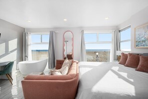 Un dormitorio moderno con una cama grande, un rincón de estar y una bañera.
