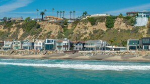 A coastal property with multiple houses, a rocky shoreline, and a view of the ocean. - Oceanfront Family Home with Firepit on the Sand (Capistrano Beach)