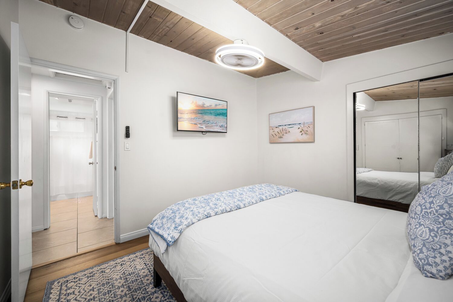 Ein Schlafzimmer mit Bett, Nachttisch, Spiegel und einer Tür zu einem Badezimmer.