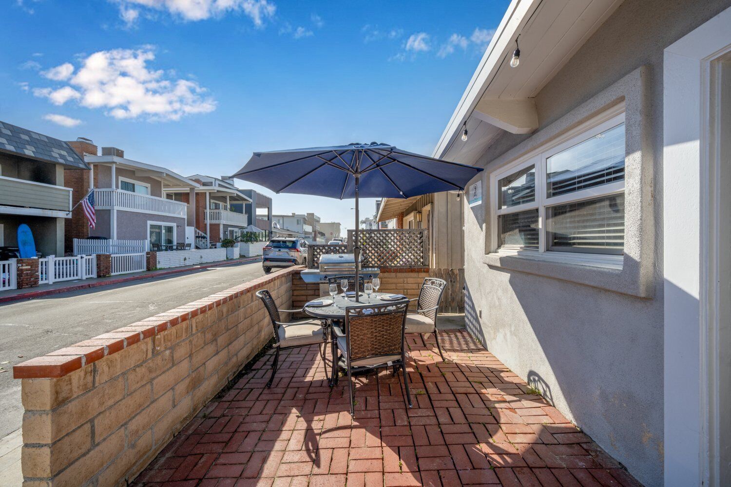 A patio with a table and chairs, an umbrella, and a brick wall.
