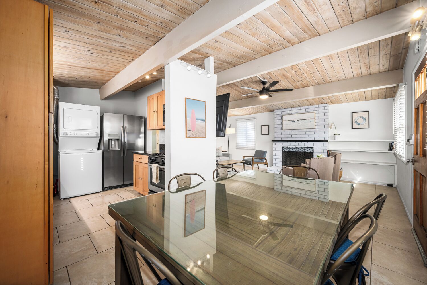 A modern kitchen with a central island, a dining area with a glass table, and a living space with a fireplace.