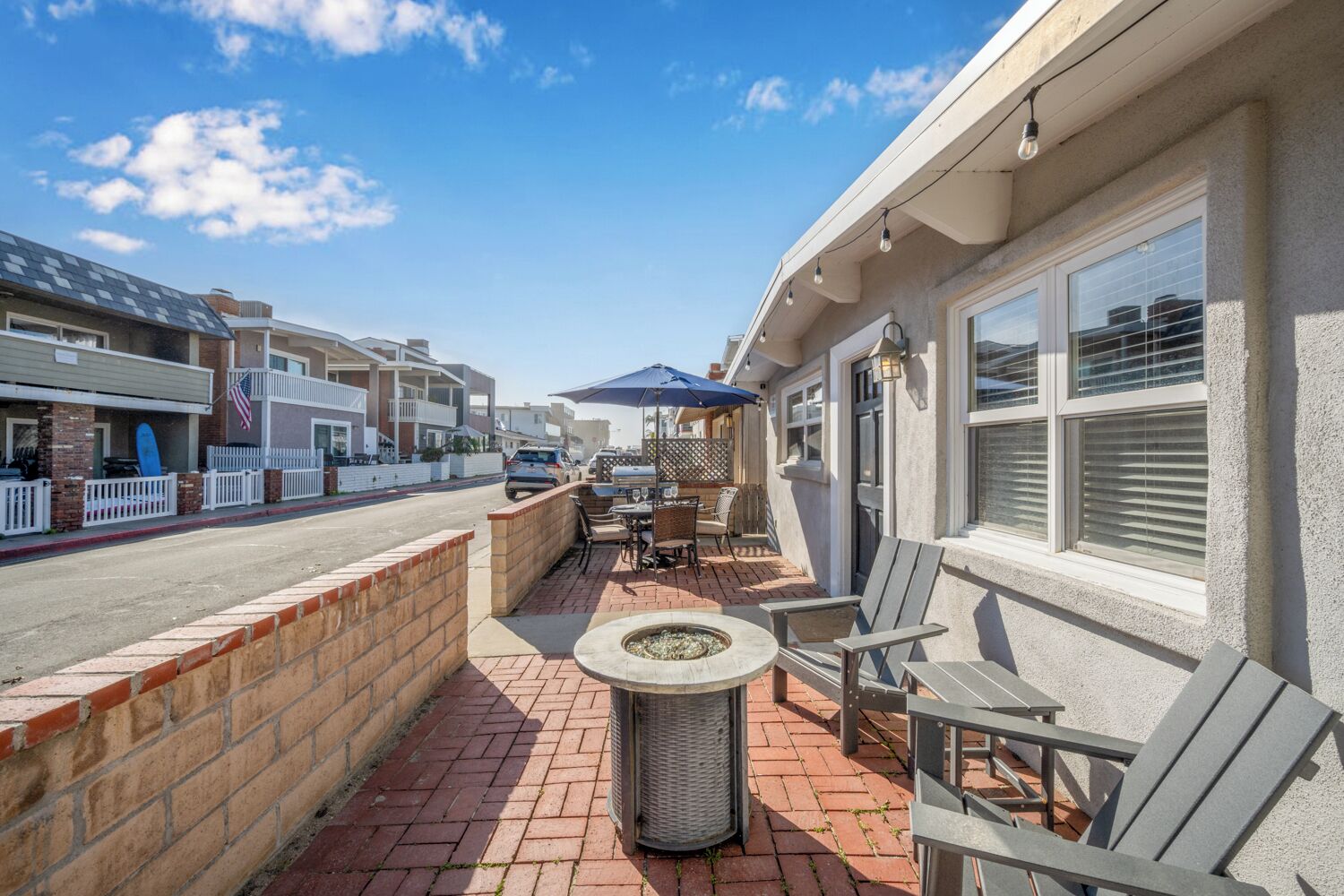 A patio with outdoor seating, a fire pit, and a view of the street.