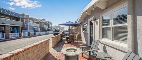 A patio with outdoor seating, a fire pit, and a view of the street.