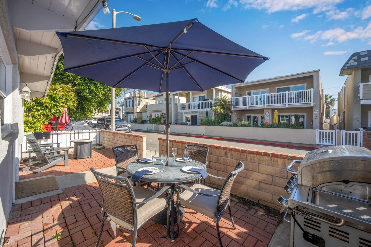 Un patio al aire libre con una mesa redonda, sillas y una parrilla.