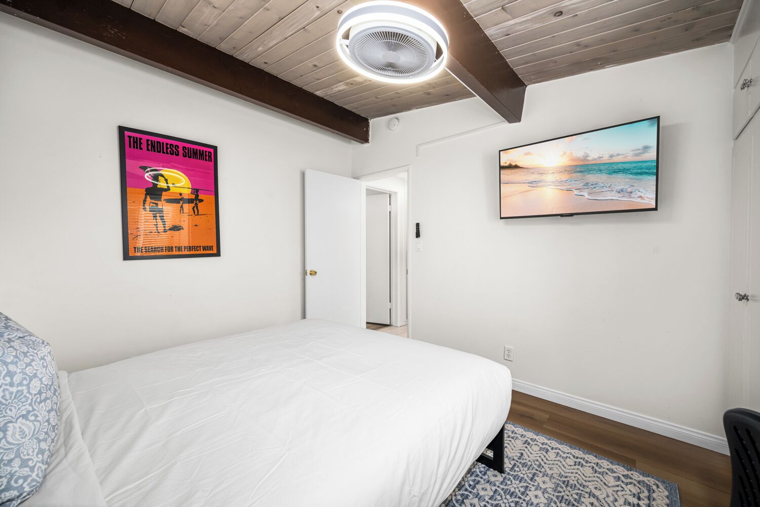 Une chambre à coucher avec un lit, une affiche, un téléviseur et une porte.