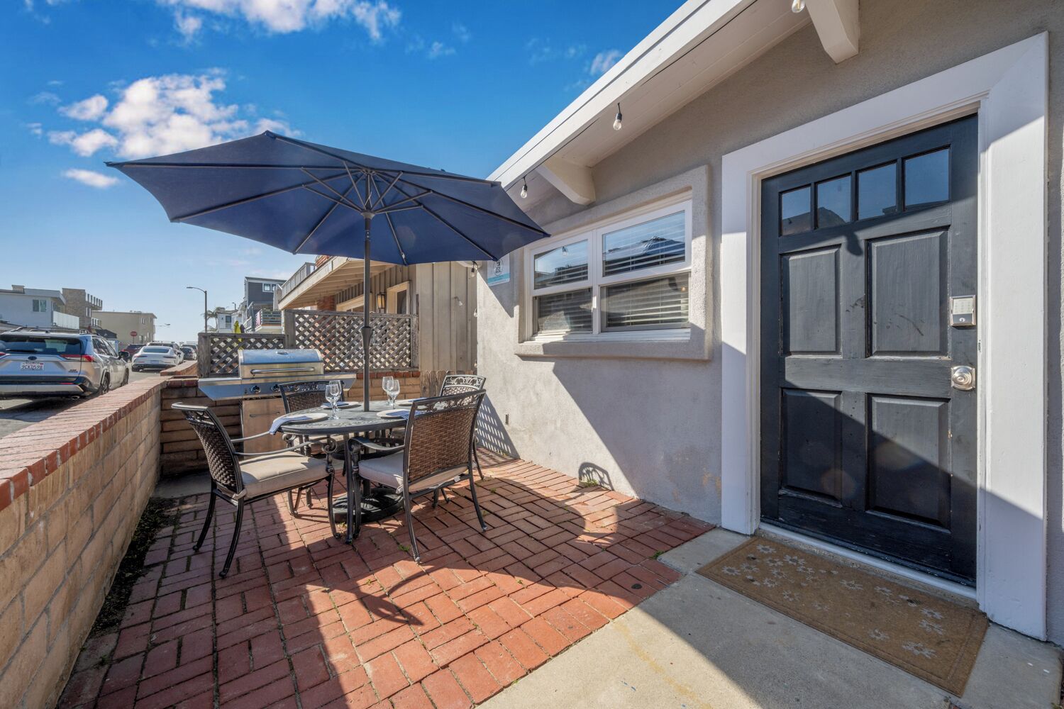 A patio with a table and chairs, an umbrella, and a grill.