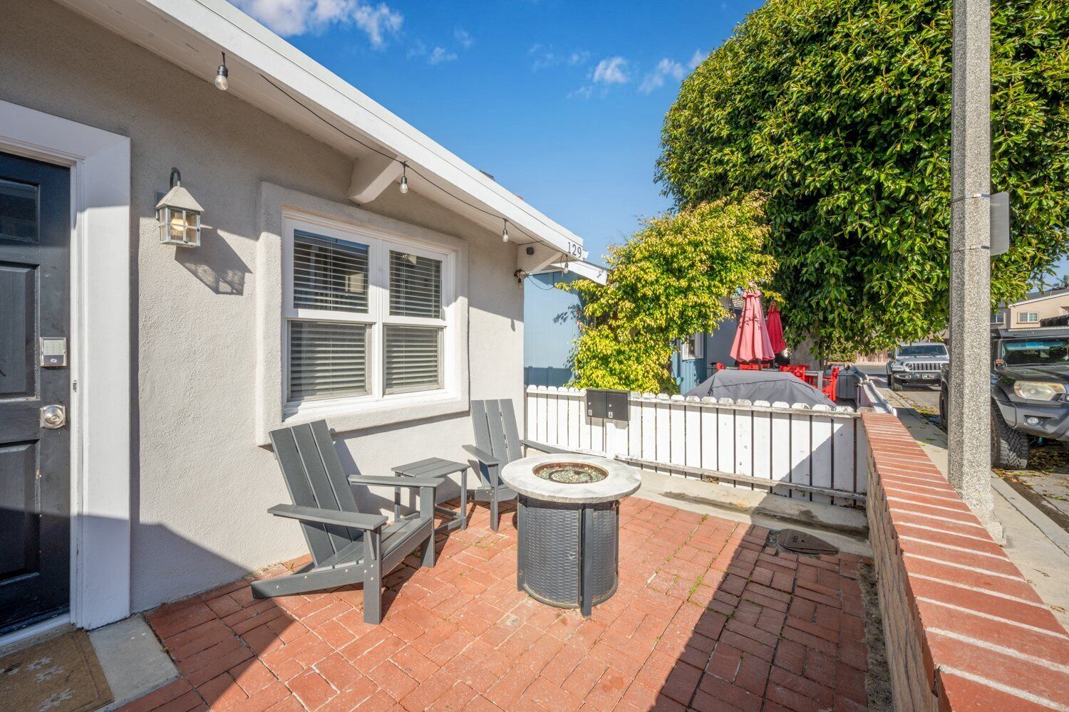 A patio with outdoor seating, a fire pit, and a view of the street.