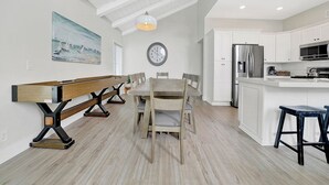 Een moderne keuken met witte kasten, een roestvrijstalen koelkast en een houten eettafel met stoelen.