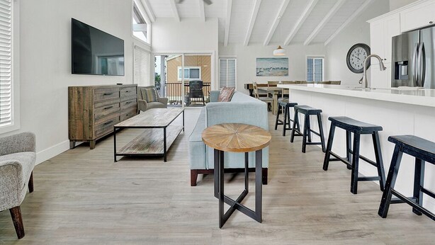 Een ruime keuken met een groot eiland, barstoelen en een plafondventilator.