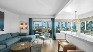 A modern living room with a sectional sofa, a coffee table, and a dining area with a bar. - Seaside 1 BR Escape on the Iconic Newport Boardwalk (Newport Beach)