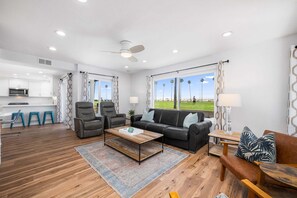 Un salon moderne avec un canapé, des fauteuils, une table basse et une vue sur l’extérieur.
