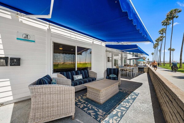 A seaside hotel with outdoor seating, a covered patio, and a view of the ocean.