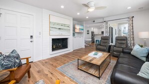Una sala de estar moderna con chimenea, sofás de cuero, una mesa de centro y un televisor.