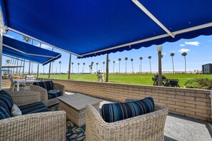 A covered patio with wicker furniture and a view of a golf course.