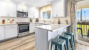 Una cocina moderna con armarios blancos, electrodomésticos de acero inoxidable y una isla grande con taburetes de bar.