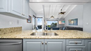 A kitchen with granite countertops, a stainless steel sink, and light gray cabinets.