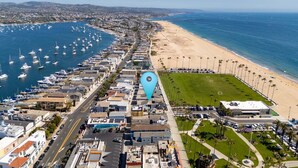Vista aérea de una ciudad costera con puerto deportivo, playa y zona urbana.