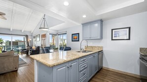 Una cocina moderna con encimeras de granito, gabinetes grises y una isla grande.