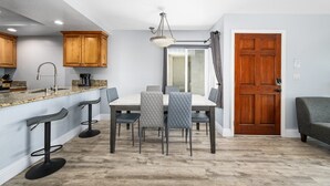 Eine moderne Küche mit Granit Arbeitsplatten, Holzschränken und einer Bar mit Hockern.