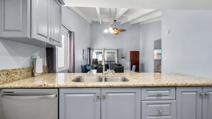 A kitchen with granite countertops, stainless steel appliances, and light gray cabinetry. - Balboa Peninsula Hidden Gem with Private Balcony & Stunning Views (Newport Beach)