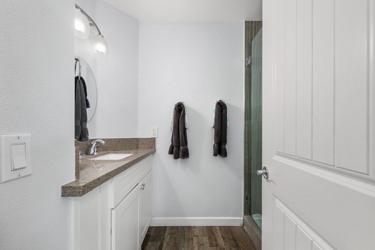 A small bathroom with a sink, mirror, and two towels hanging on the wall.