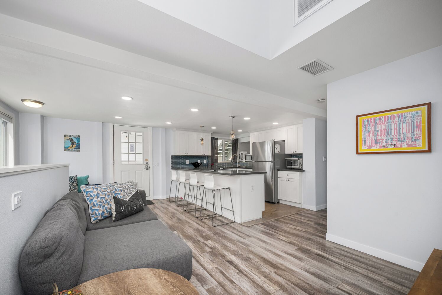 A modern kitchen with white cabinets, stainless steel appliances, and a bar area with stools.
