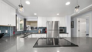 A modern kitchen with white cabinets, stainless steel appliances, and a central island. - Perfect Surf Casa in Newport Near Beach and Pier (Newport Beach)