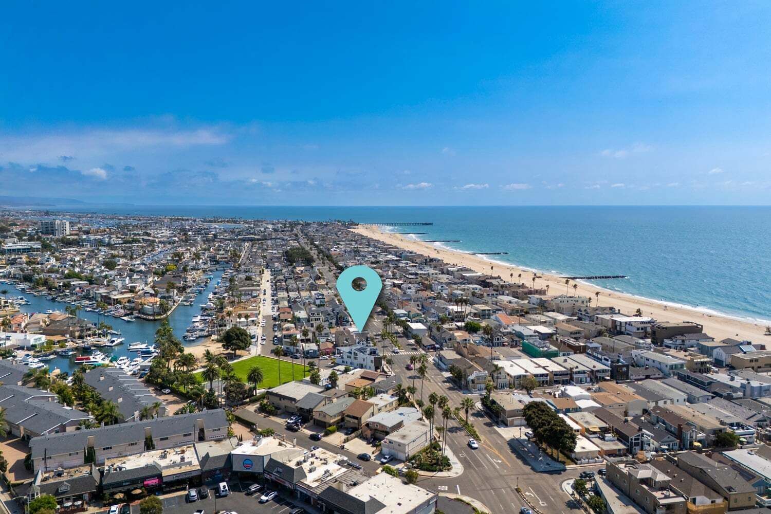Luchtbeeld van een kustplaats met een jachthaven, strand en een dichtbebouwd woongebied.