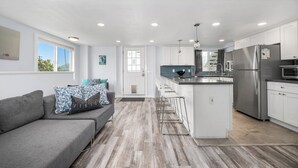A modern kitchen with white cabinetry, a stainless steel refrigerator, and a bar area.